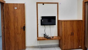 Une pièce avec une porte en bois portant le numéro 102, un téléviseur fixé sur un cadre en bois et un meuble en bois.