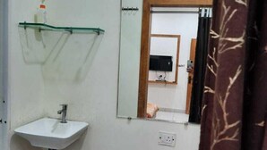 Une salle de bain avec un lavabo blanc, un miroir et un espace douche.