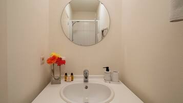 A bathroom with a round mirror, a white sink, and toiletries.