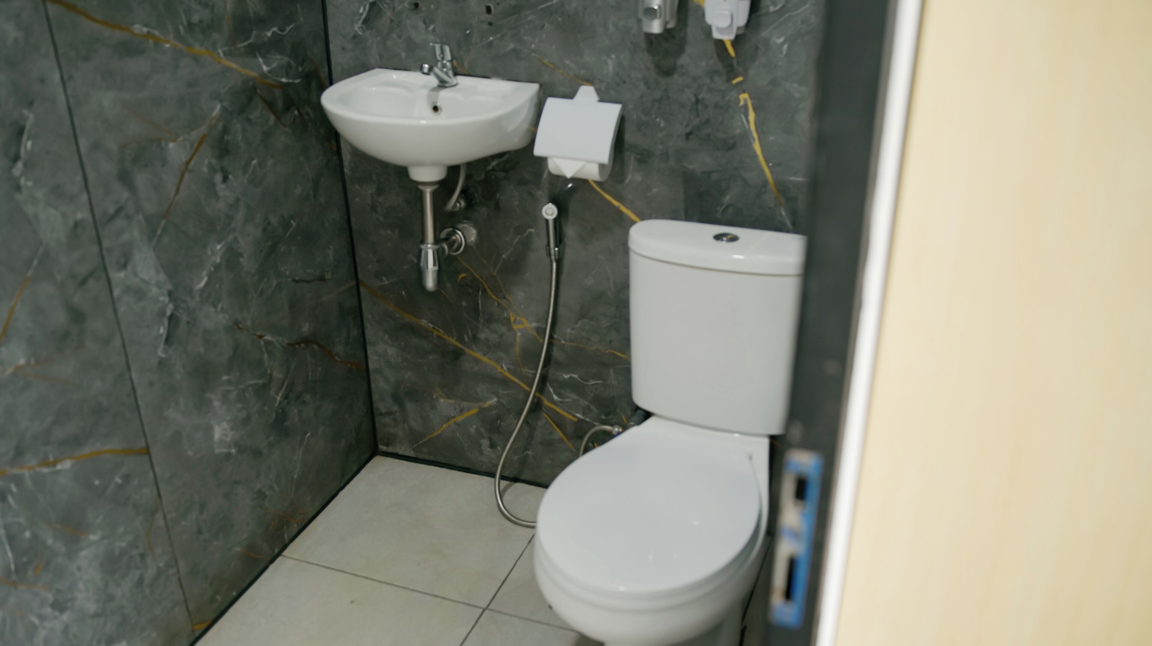 Ein Badezimmer mit einem weißen Waschbecken, einer Toilette und sichtbarer Sanitärinstallation.