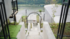 A staircase leading to a terrace with a view of a lake and boats.