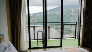 A room with a large sliding glass door leading to a balcony with a metal railing and a table.