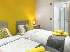 Une chambre d’hôtel avec un lit, une table de chevet avec une lampe et une cabine de douche en verre.