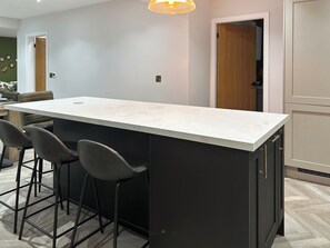 Una cocina con encimera de mármol, armarios negros y una puerta de madera.