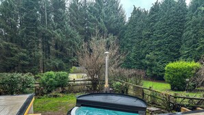A hot tub on a wooden deck with a forested background. - 3 bedroom accommodation in Brereton, Cannock Chase (Brereton, Cannock Chase)