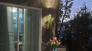 En utomhusplats med sittmöbler, bestående av ett runt bord, två stolar och en dekorativ vas med blommor.