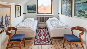 Ein Zimmer mit zwei Einzelbetten, einem Heizkörper, einem Fenster und Holzboden.