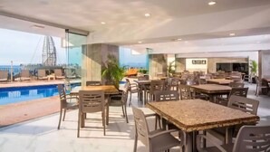 A modern indoor pool area with seating and a view of a bridge. - Confresi Palm Beach & Spa (Puerto Plata)