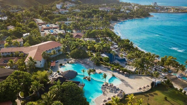 An aerial view of a resort with a large swimming pool, beach area, and ocean views. - Confresi Palm Beach & Spa (Puerto Plata)