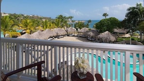 A poolside area with thatched umbrellas and lounge chairs, overlooking a beach and ocean. - Confresi Palm Beach & Spa (Puerto Plata)