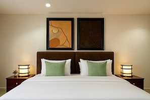 A hotel room with a large bed, two bedside tables with lamps, and two framed artworks on the wall. - Luxury 2BR Apt Central Lekki Phase 1 (Lekki)