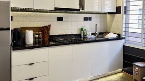 Una cucina moderna con mobili bianchi, un piano di lavoro nero e un frigorifero in acciaio inossidabile.