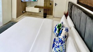 Una camera d'albergo con un letto grande, una televisione a parete, un pannello di legno, una porta e un quadro.