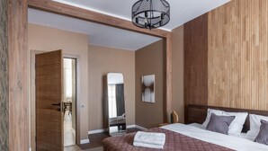 A bedroom with a large bed, wooden headboard, a mirror, and a chandelier. - Luxury apart with a view Victory Square (Minsk)