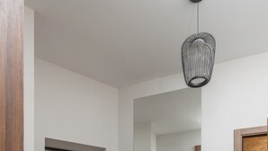 A modern hallway with wooden flooring, a white door, a bench, and a hanging light fixture. - Luxury apart with a view Victory Square (Minsk)