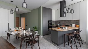A modern kitchen with a central island, dark wooden chairs, and pendant lighting. - Luxury apart with a view Victory Square (Minsk)
