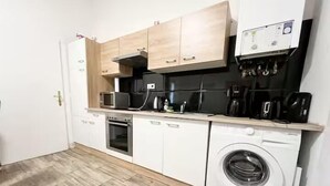 A compact kitchen with a washing machine, oven, microwave, and wooden cabinets. - Comfortable 3BR Apartment in Vienna (Vienna)