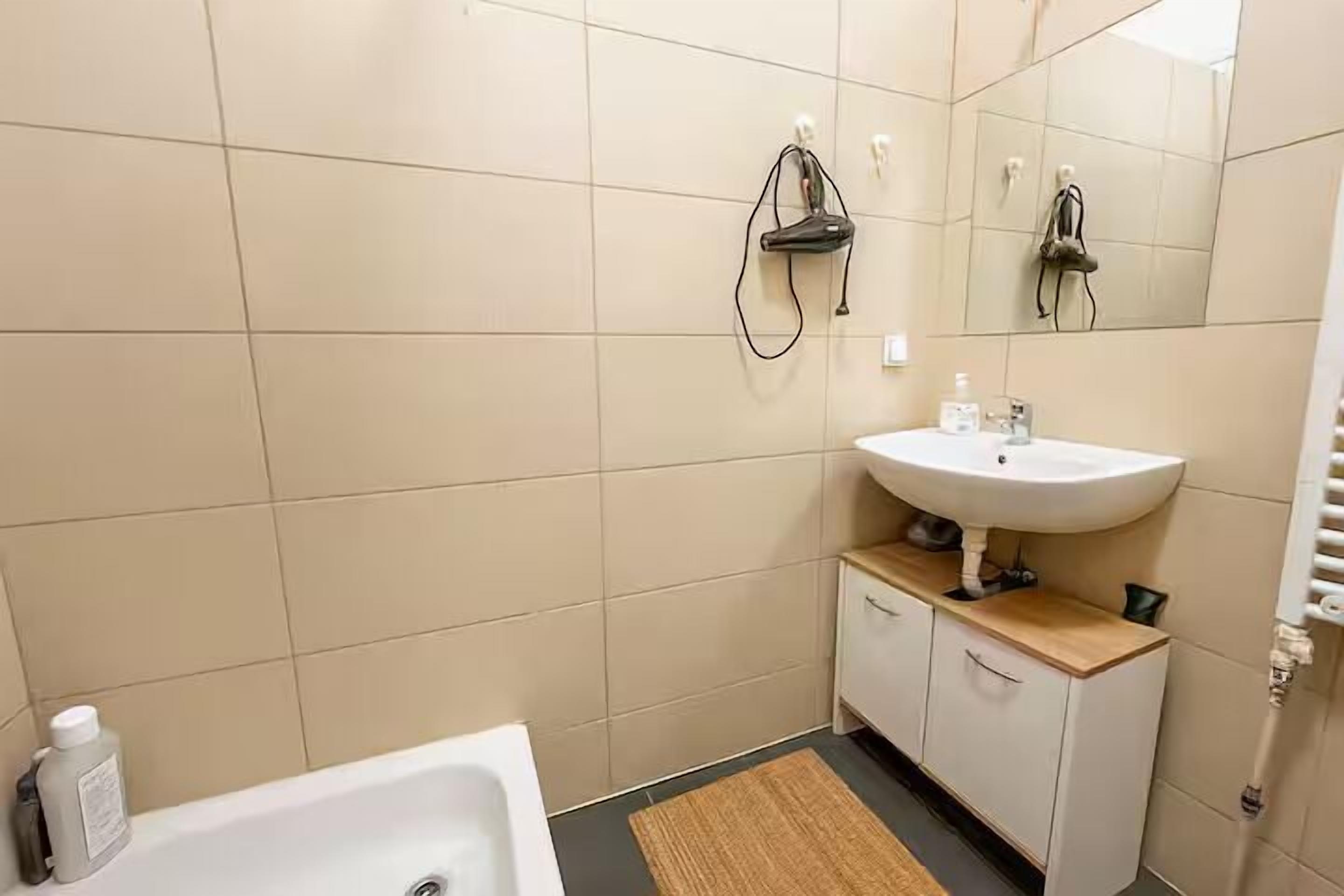 Un baño con un lavabo blanco, un espejo y una ducha.