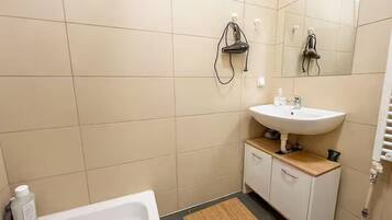 Un baño con un lavabo blanco, un espejo y una ducha.