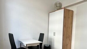 A small room with a white table and two black chairs, a wooden wardrobe, and a small trash bin. - Comfortable 3BR Apartment in Vienna (Vienna)