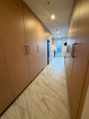 A modern kitchen with a large island, wooden cabinets, and a marble floor. - Brand-New 1BR Apartment near Te Kaha Stadium (Christchurch)