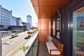 Un balcon donnant sur une rue de la ville, un banc et un bâtiment avec une enseigne.