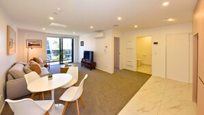 Una sala de estar moderna con sofá, televisión y comedor.