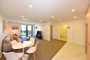 A modern living room with a sofa, TV, and dining area.