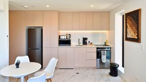 Een moderne keuken met een ingebouwde oven, een koelkast en een eethoek met een witte tafel en stoelen.
