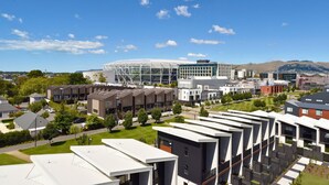 Een modern gebouwcomplex met meerdere woningen, een grote glazen constructie en omliggend groen.
