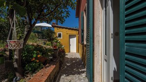 A narrow alleyway with a yellow building, a tree, and a hanging macrame chair. - La Torre sul Ponte, Seaview, Garden (Monte Argentario)