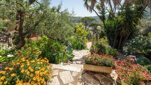 A garden with stone pathways, potted plants, and a variety of flowers. - La Torre sul Ponte, Seaview, Garden (Monte Argentario)