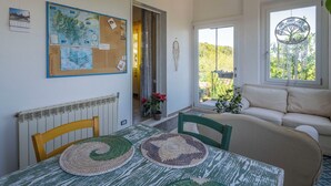A room with a table, chairs, a sofa, a window with a tree decoration, and a bulletin board with maps and notes. - La Torre sul Ponte, Seaview, Garden (Monte Argentario)
