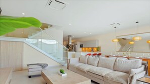 Una sala de estar moderna con sofá, mesa de centro y una escalera que sube a un nivel superior.