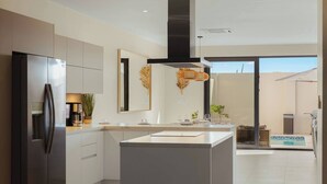 Una cocina moderna con una isla central, electrodomésticos de acero inoxidable y vistas a una piscina.