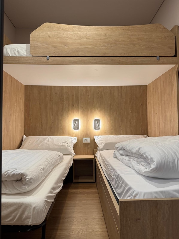 A bunk bed room with wooden walls, two bedside tables, and wall-mounted lights. - Camping Dolomiti (Dimaro Folgarida)