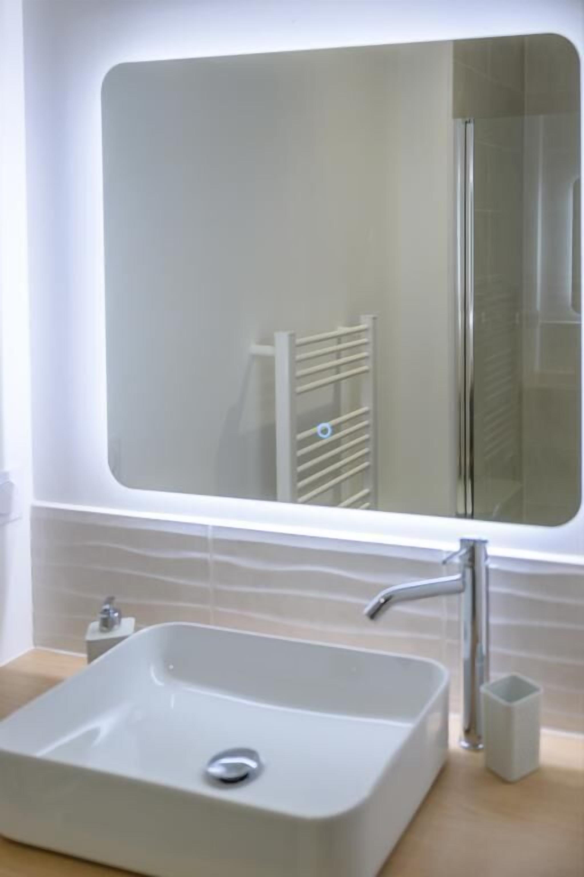 Une salle de bain avec un lavabo blanc, un miroir et un porte-serviettes.