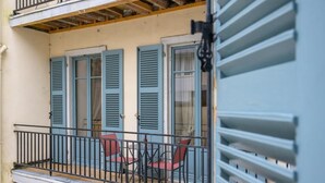 A balcony with two tables and four chairs, a wooden ceiling, and a window with blue shutters. - Cœur de Pau - Clim et Parking - L'Odyssée (Pau)