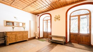 Habitació amb terres i sostre de fusta, un gran mirall, un armari, una banca i dues portes de fusta amb panells de vidre.