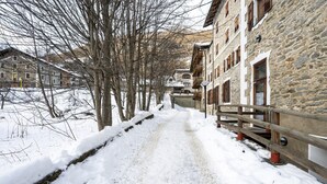 Un camí cobert de neu, delimitat per edificis de pedra amb baranes i balcons de fusta.
