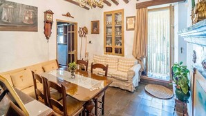 A dining area with a wooden table, chairs, and a chandelier. There is a checkered sofa and a cabinet with glass doors. - Holiday Home in Archidona with private pool (Archidona)