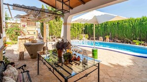 An outdoor patio with a glass table, seating, and a pool. - Holiday Home in Archidona with private pool (Archidona)