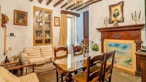 A dining area with a glass-top table, wooden chairs, a sofa, and a fireplace with a painting. - Holiday Home in Archidona with private pool (Archidona)