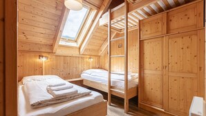 Una cabaña de madera con dos literas, un tragaluz y un armario de madera.