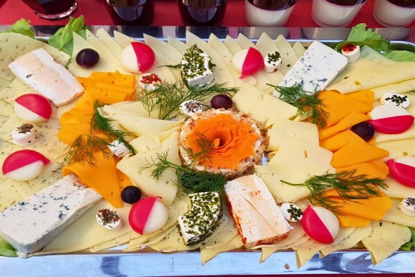 A platter of assorted cheeses, fruits, and garnishes.