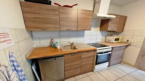 A kitchen with wooden cabinets, a dishwasher, an oven, and a microwave. - Cosy apartment in the Oderbruch (Bleyen-Genschmar)