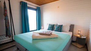 A bedroom with a bed, a window with curtains, a bedside table, and a wall-mounted shelf. - Luxury Forest Lodge with Private Garden (Ravels)