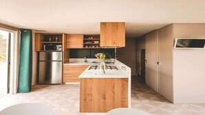 Une cuisine moderne avec des meubles en bois, un réfrigérateur en acier inoxydable et une cuisinière à gaz.