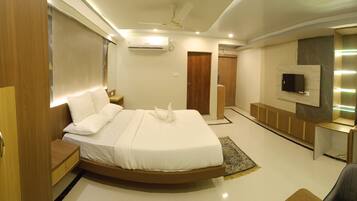 A modern bedroom with a curved bed, a TV mounted on the wall, and a ceiling fan.