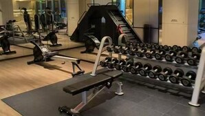 A modern gym with exercise equipment, a bench press, and a rack of dumbbells. - Silk Road-Fu Tea Town Boutique Homestay (Xianyang)